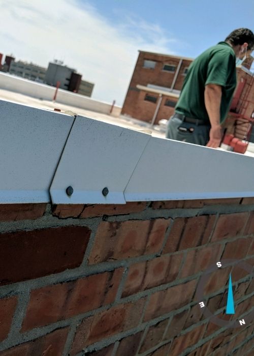 Deteriorated brick parapet wall showing cracked coping and failed mortar joints on New Jersey building